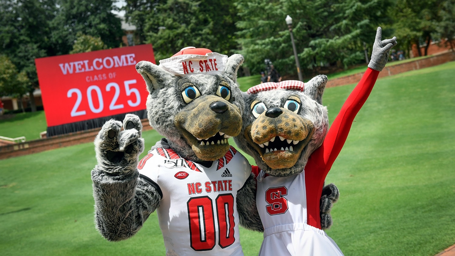 Mr. and Ms. Wuf pose in front of a sign reading "Welcome Class of 2025."